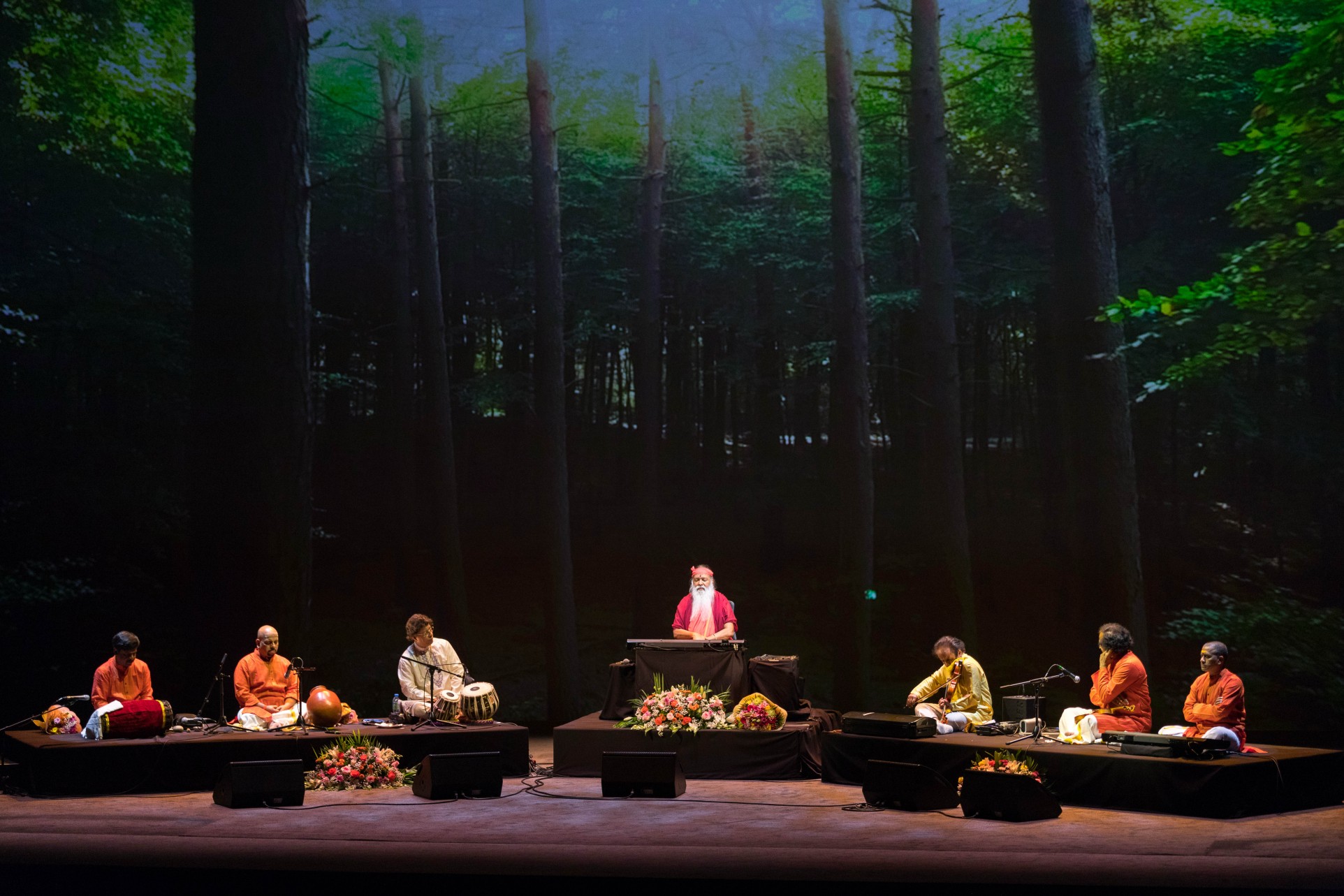Concert — Sri Swamiji with ensemble, tall forest backdrop