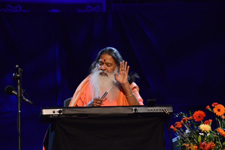 Sri Swamiji — raising hand in blessing on stage